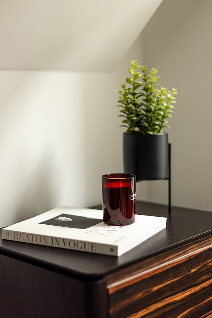 Book, candle, and potted plant on a wooden nightstand