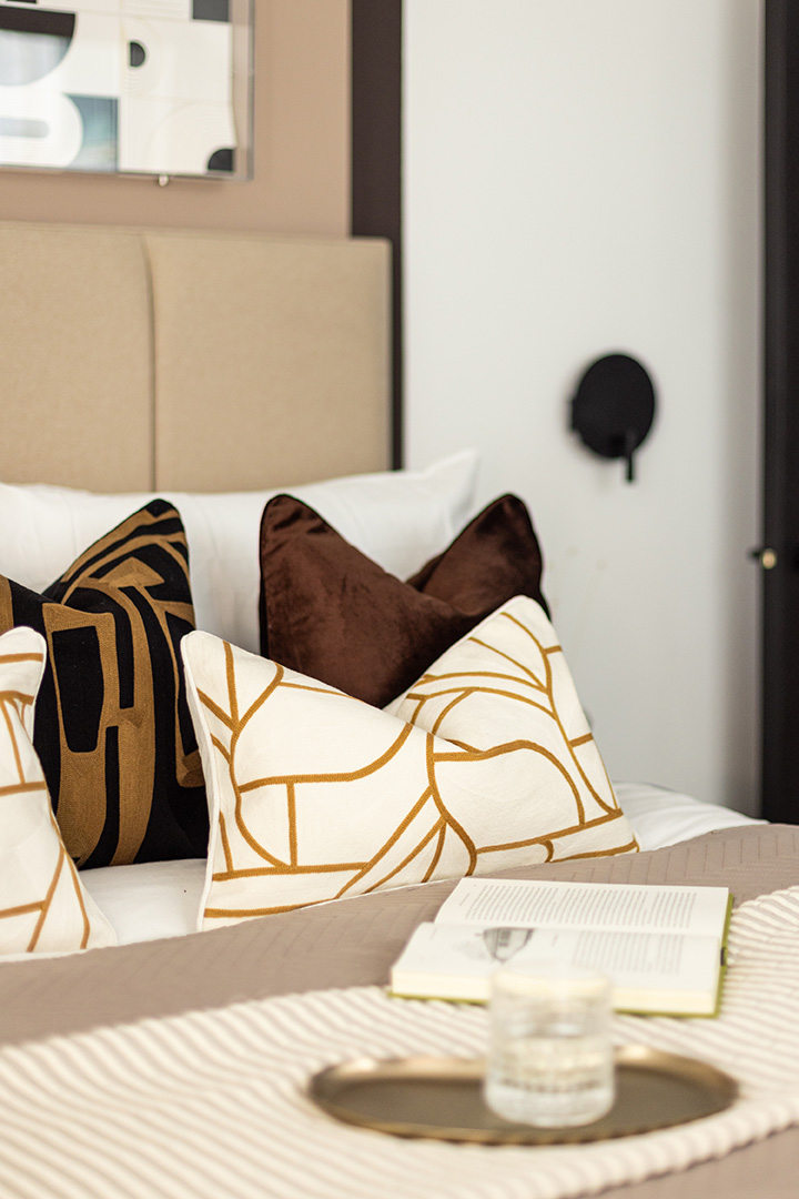 Cozy bed with patterned pillows, a book, and a drink