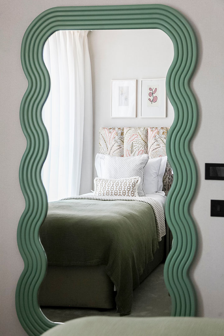 Wavy green mirror reflecting bedroom view