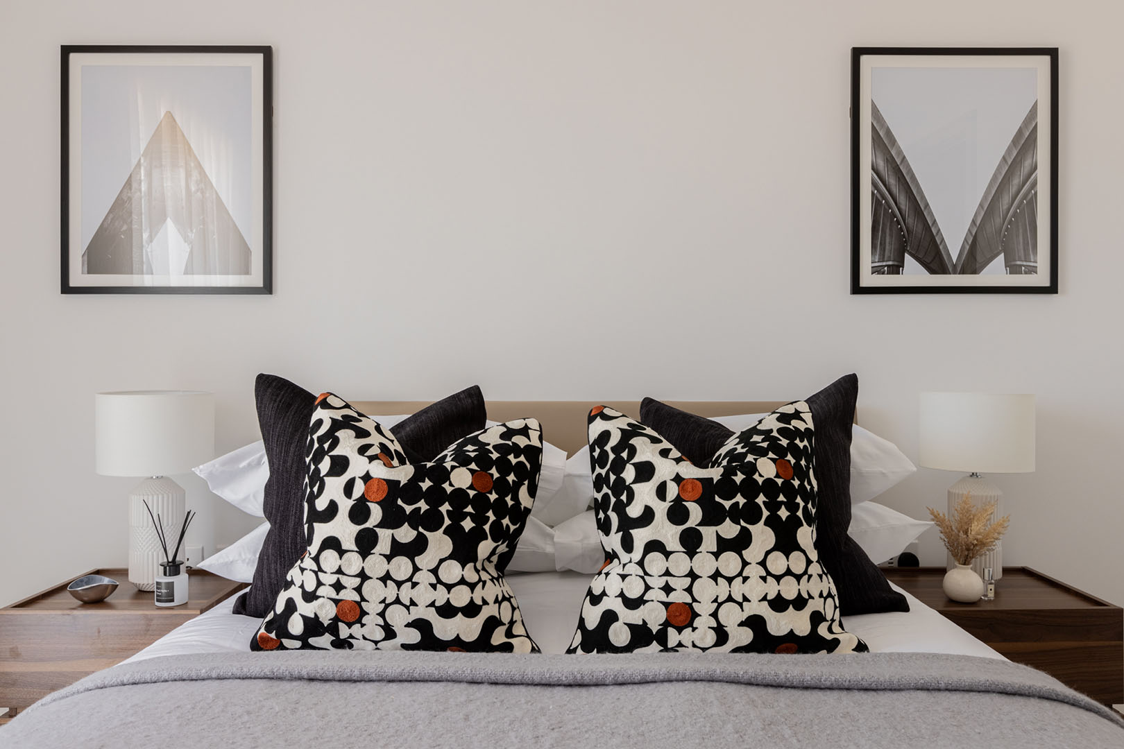 Modern bedroom with framed prints, patterned pillows, and lamps