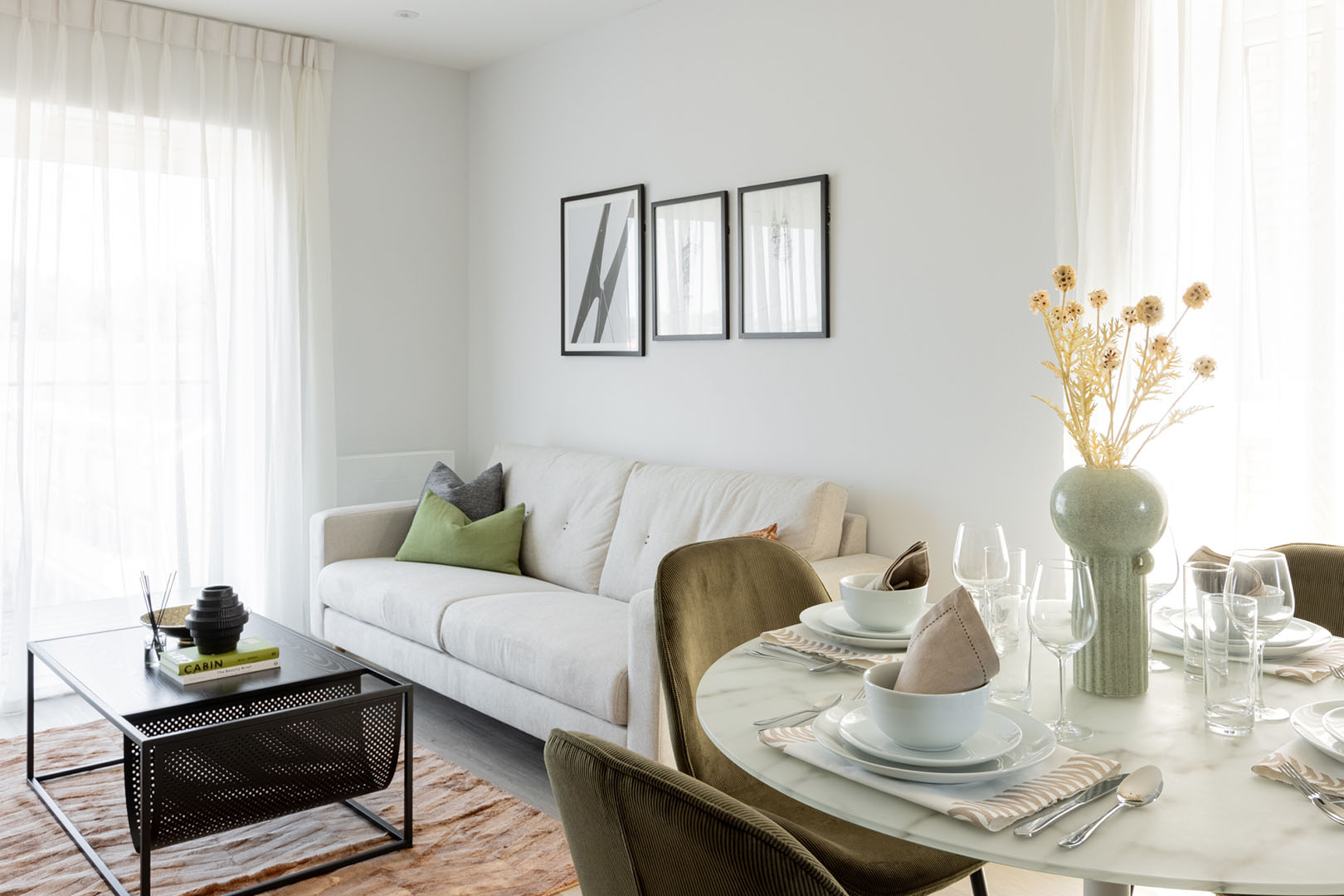 Open-plan living space with a sofa, dining table, and artwork