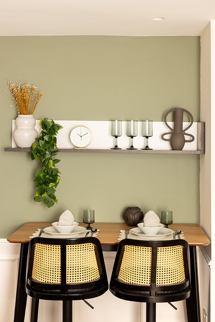 Small dining nook with a green wall and a shelf