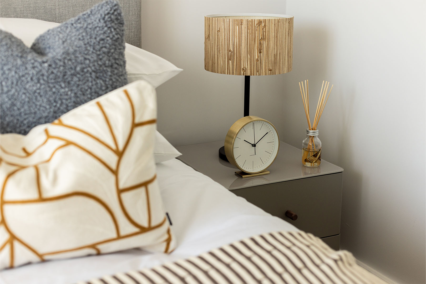 Detailed bedside decor - lamp, textured pillow, clock