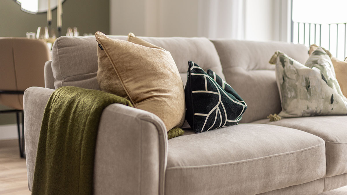 Beige sofa with patterned and velvet pillows at Pintail Heights