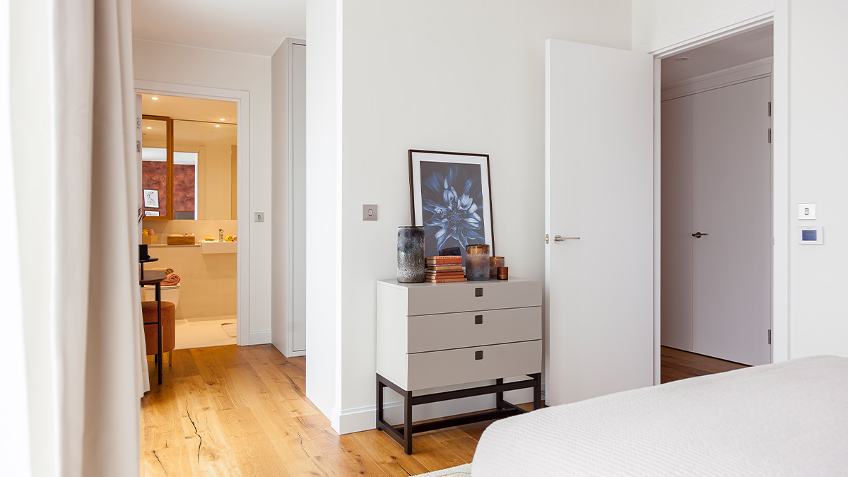Modern bedroom with white walls, wood floors, and a stylish dresser