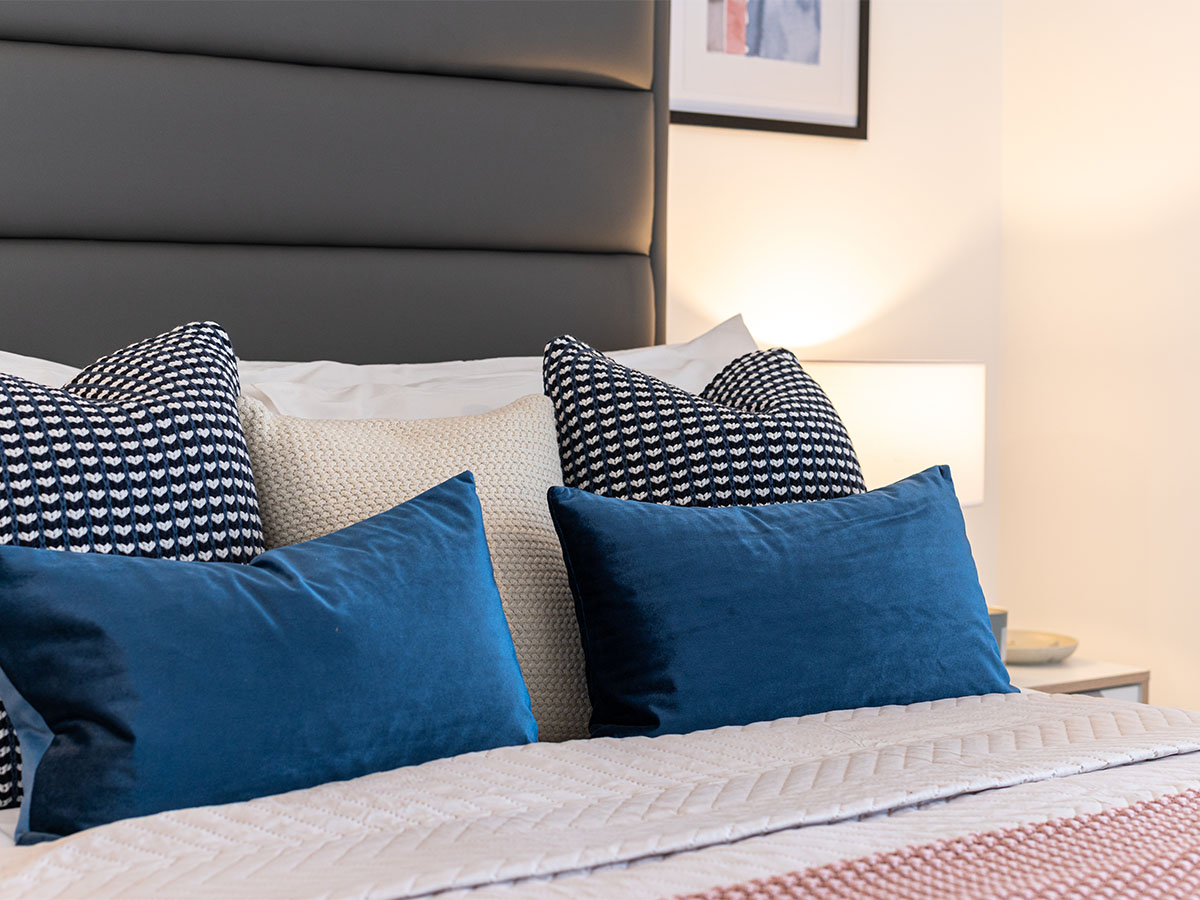 blue and patterned decorative pillows on bed at Hendon Waterside, London