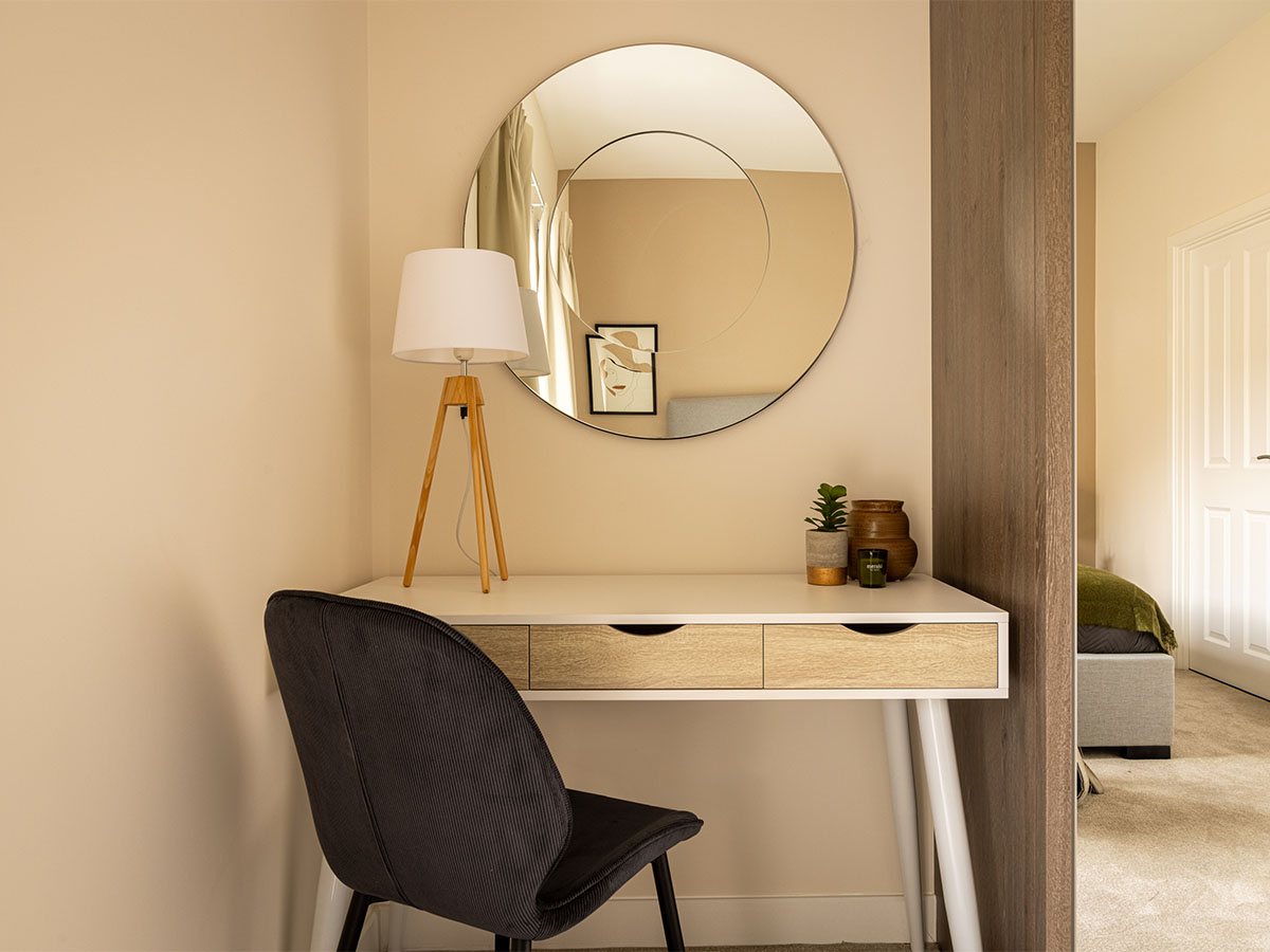 Round mirror above a white and wood desk