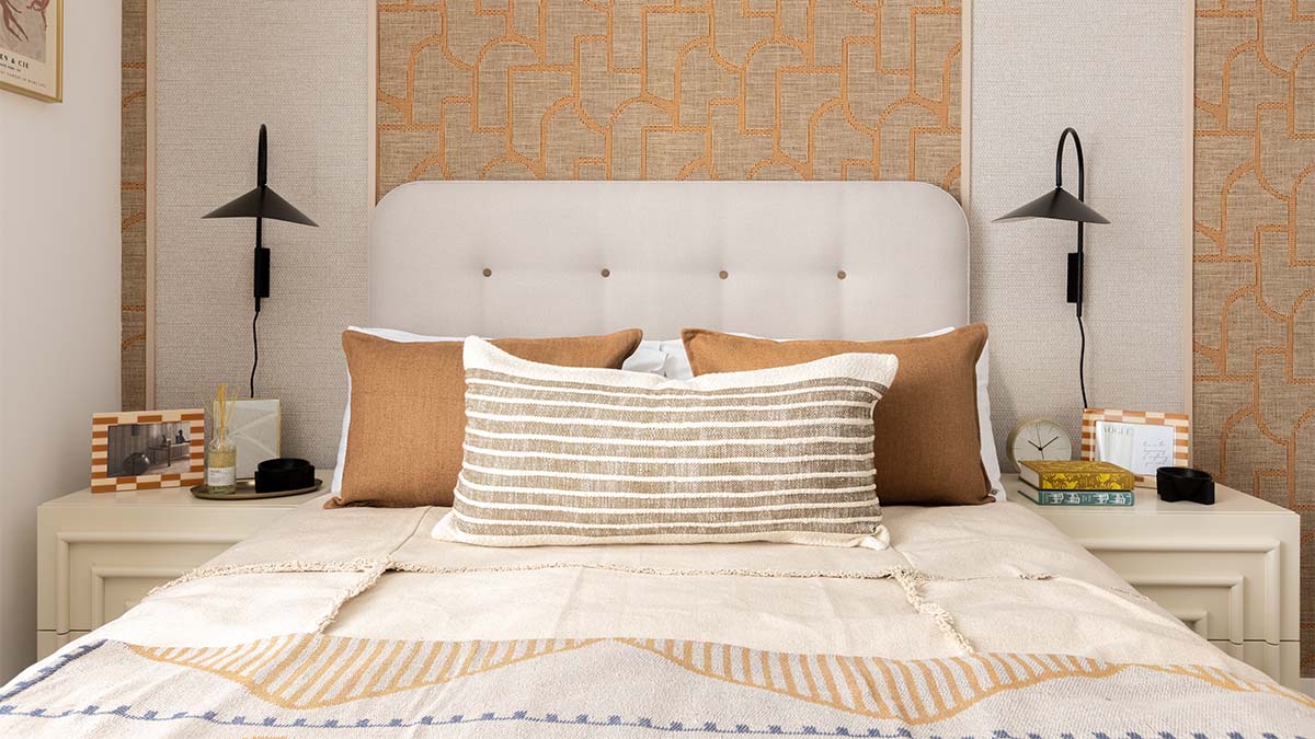 White bed with brown pillows and patterned throw