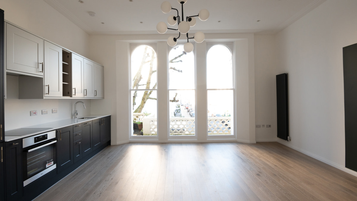 Kitchen area in an unfurnished room with arched windows