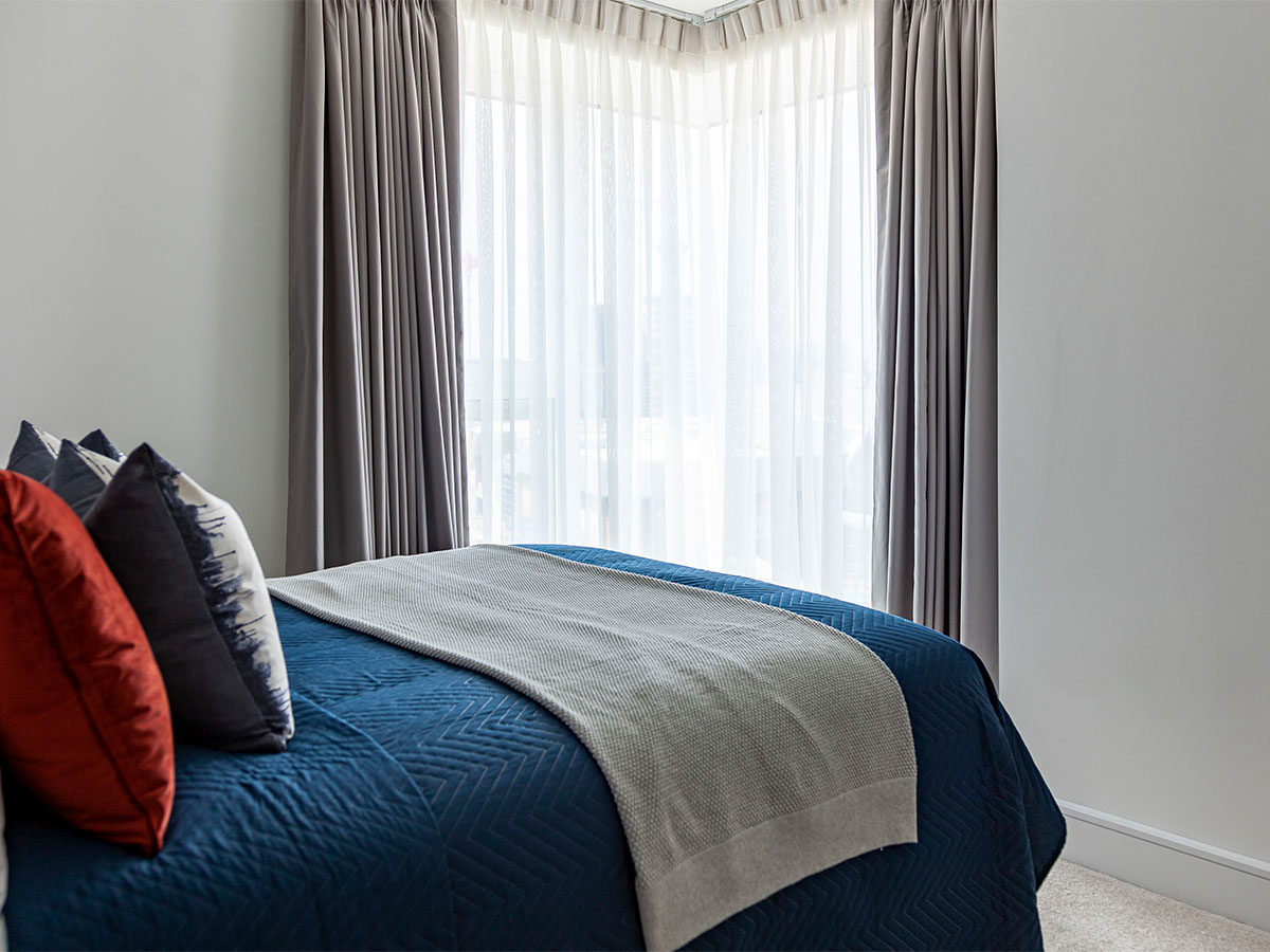 Bed with blue quilt and decorative cushions