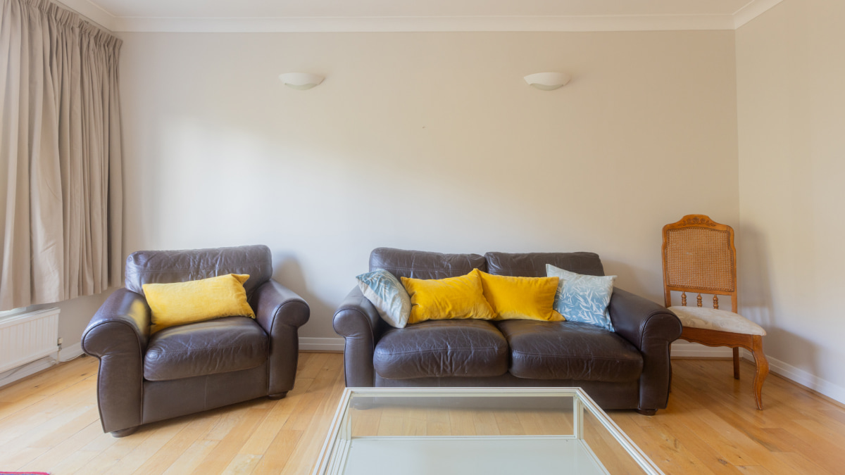 Living room before staging with brown leather sofa and armchair