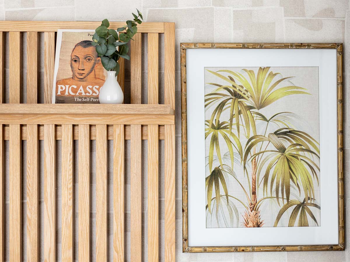Close-up of oak headboard shelf with decor and framed palm print