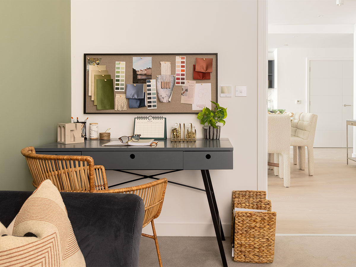 Home office nook with grey desk, rattan chair, and mood board
