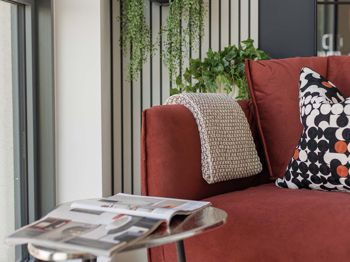 Red sofa with patterned cushion and knitted throw at Haydon development