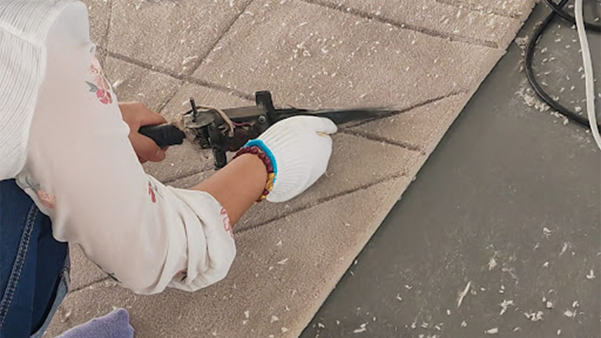 Craftsperson shaping carpet with tool