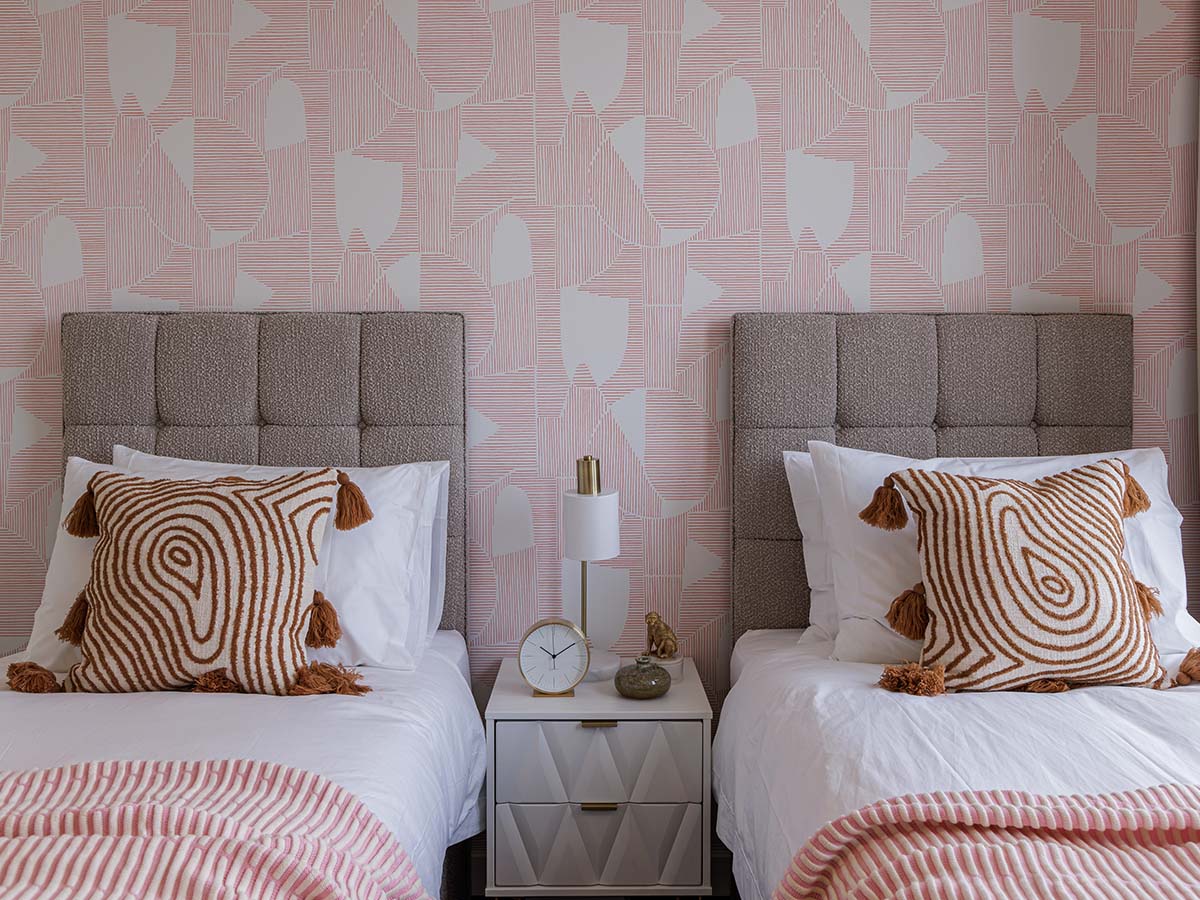 Triptych Bankside twin beds with textured pink geometric wallpaper and lamp