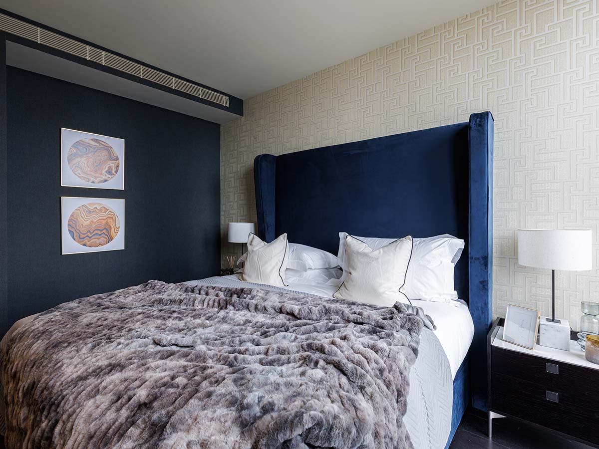 Triptych Bankside bedroom with blue velvet headboard and fur blanket