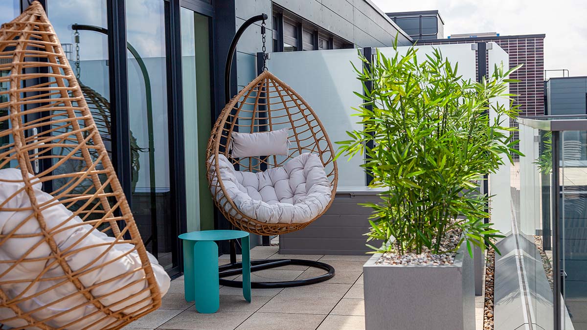 Balcony with hanging rattan egg chairs and potted bamboo plants