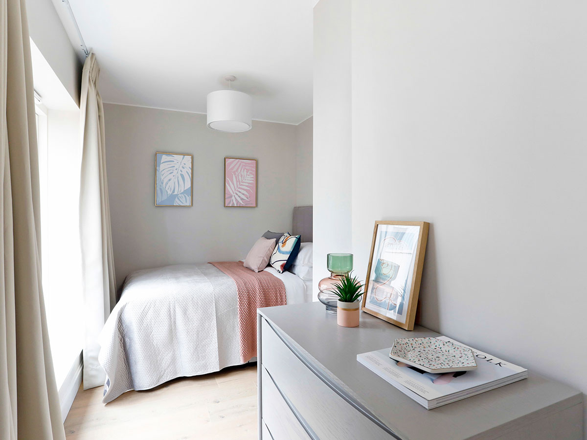A-smaller-bedroom-with-pink-accents-pastel-leaf-artwork-and-minimal-styling