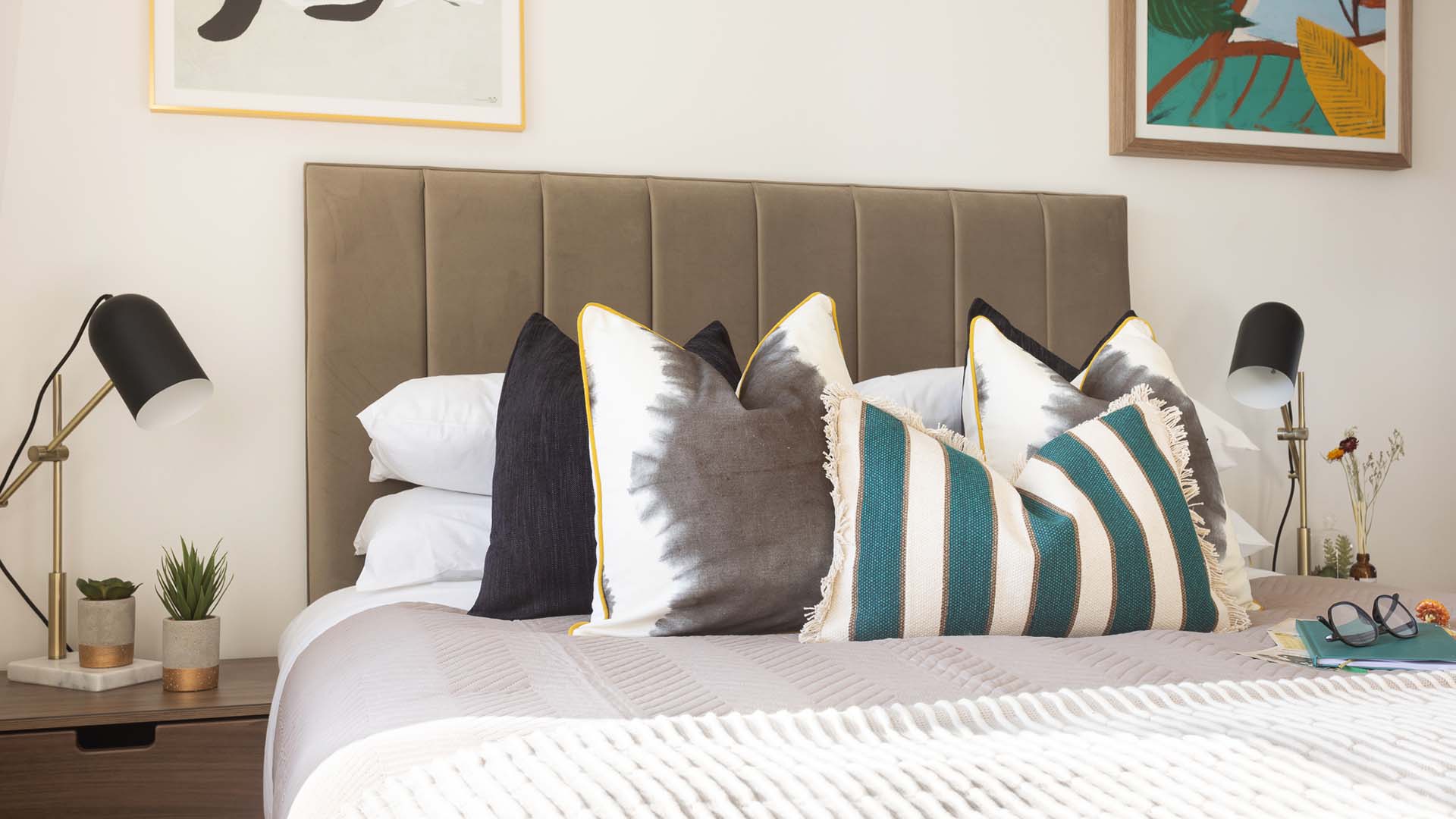 Close-up of modern bed with patterned cushions and lamps