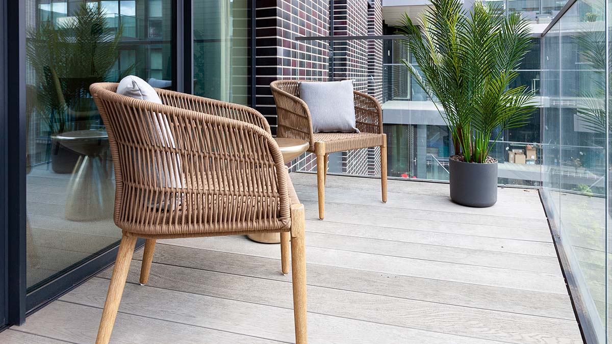Balcony with woven chairs, potted plant, and glass railing