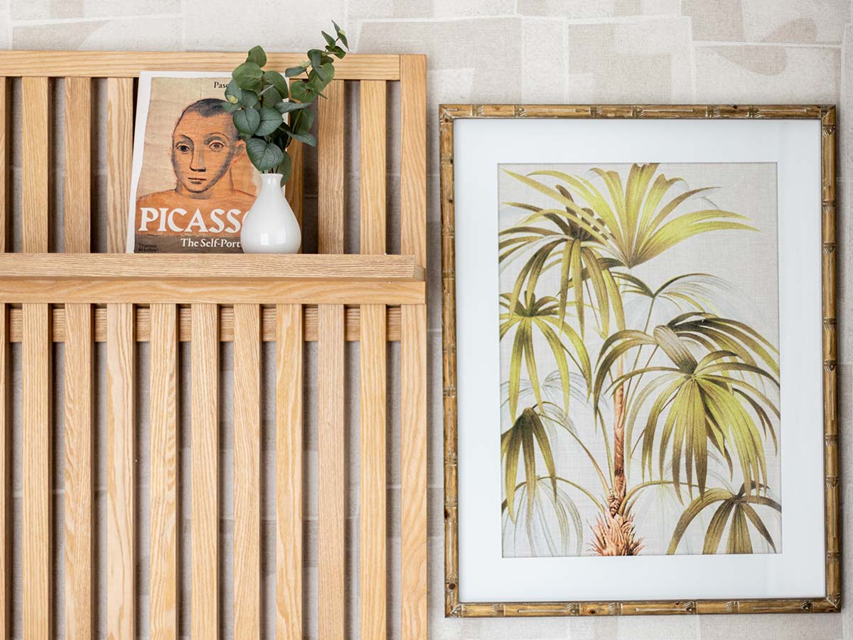 Close-up of a stylish wooden slatted headboard with art and a book, showcasing exquisite furnishing details in a Fulton and Fifth London flat bedroom