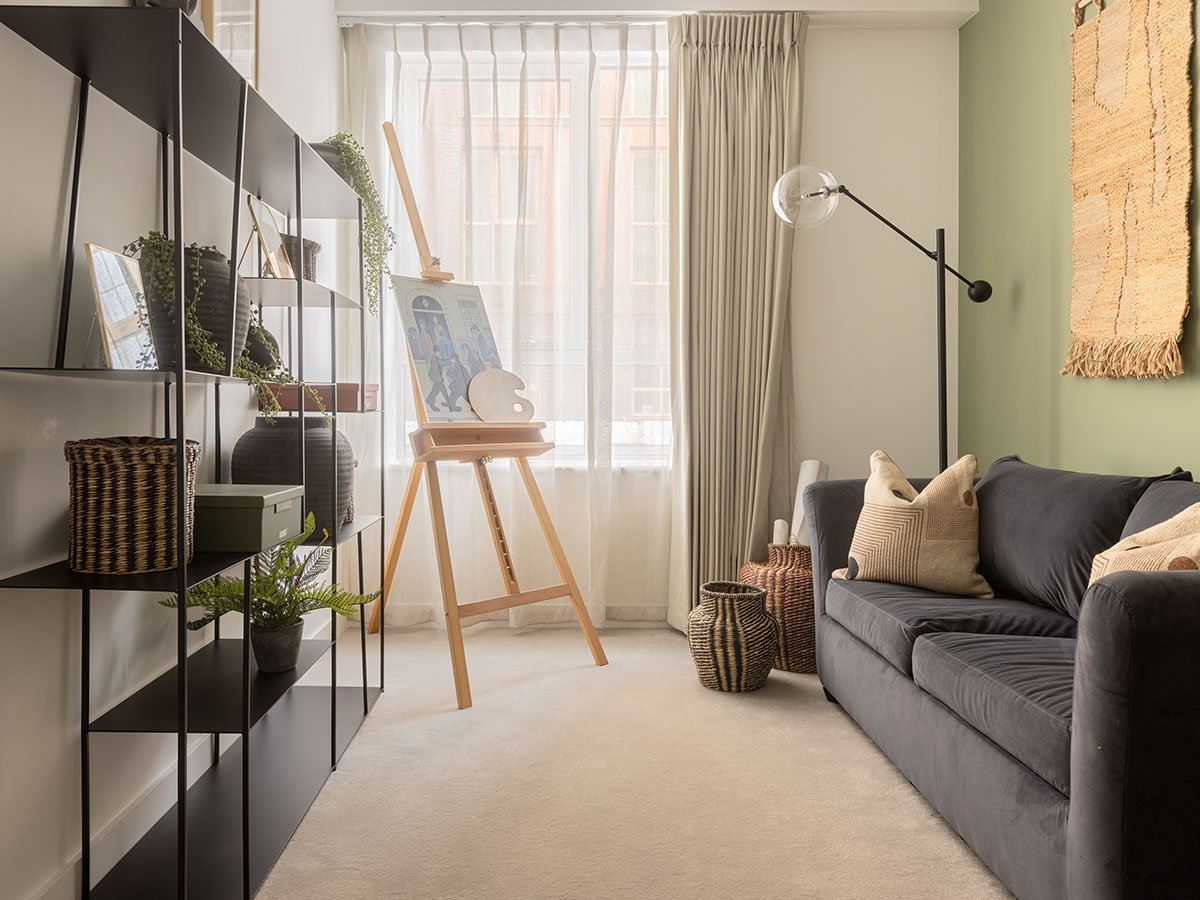 Modern living room corner in a Fulton and Fifth London flat, featuring a stylish black shelving unit, easel, and neutral sofa, expertly furnished by InStyle Direct