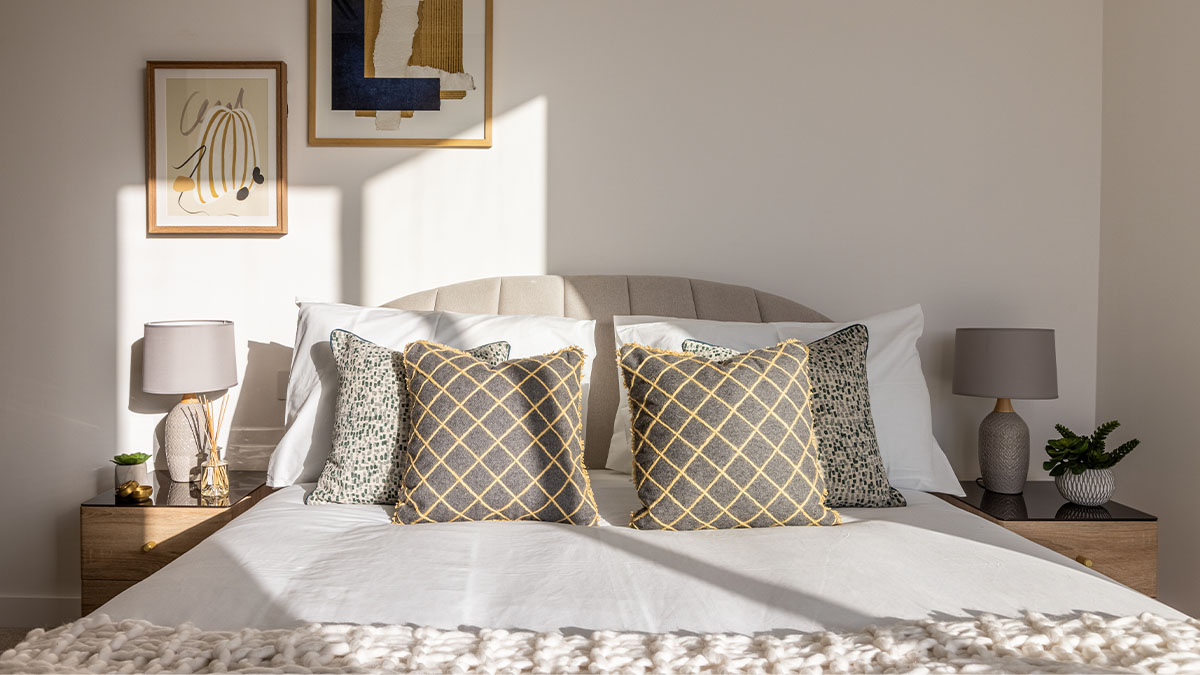 Stylish London bedroom with neutral tones and geometric patterned cushions, demonstrating professional furnishing for increased rental appeal