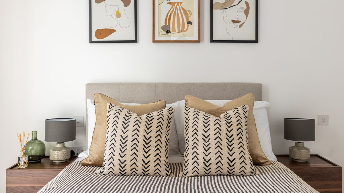 Well-appointed London bedroom with a striped quilt and patterned pillows, showcasing professional furnishing for overseas investors