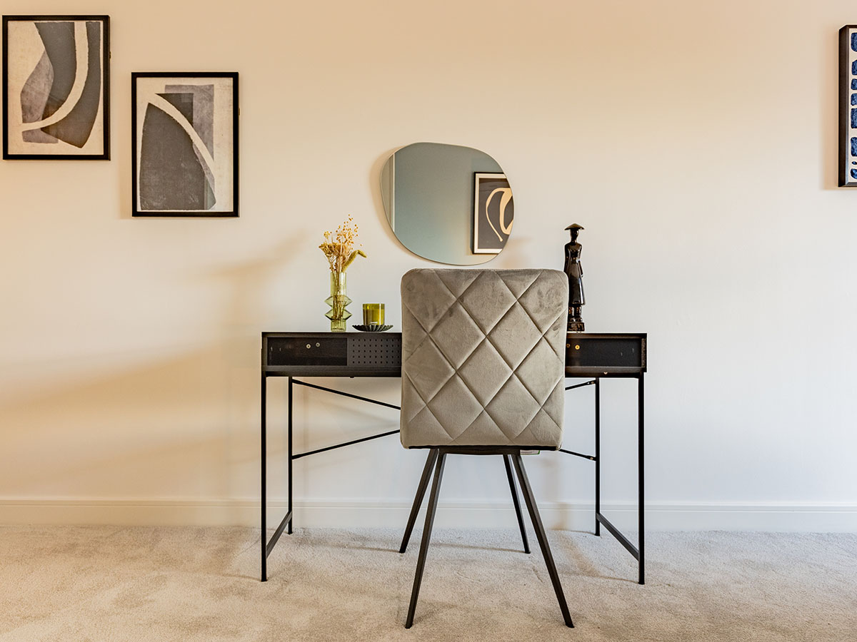 Elegant black metal dressing table or desk with a grey velvet chair and subtle decor in a furnished London flat, perfect for tenants