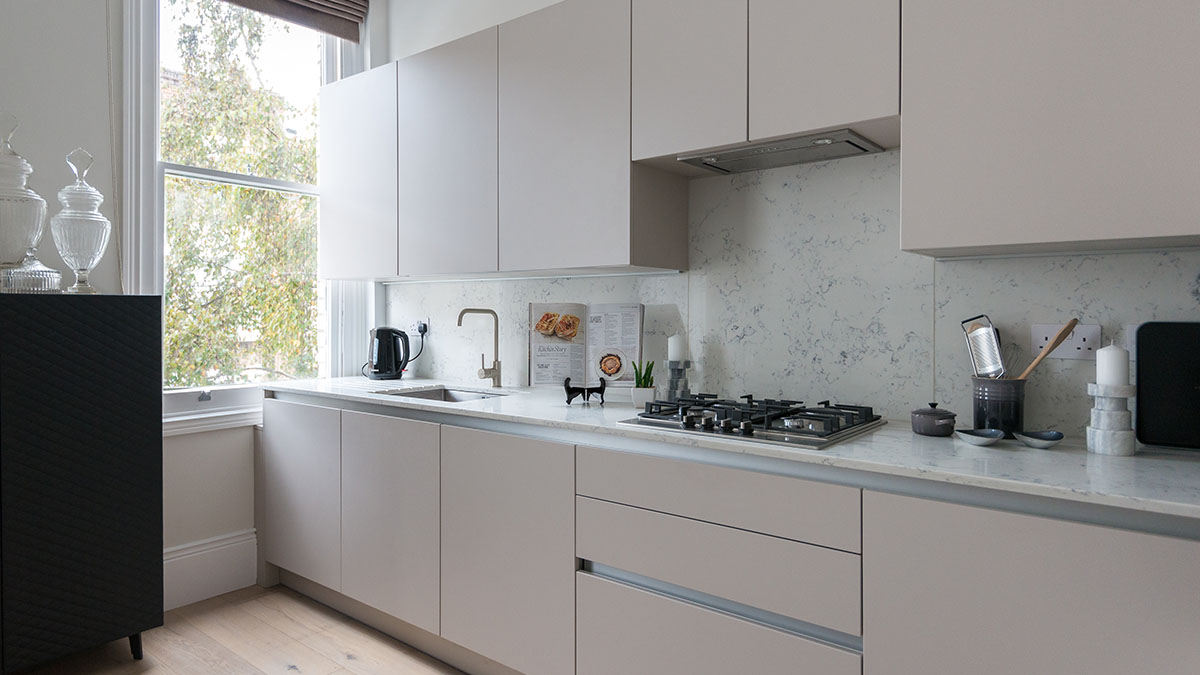 Bright, modern kitchen in a renovated London Victorian house, featuring light cabinetry, integrated appliances, and large window