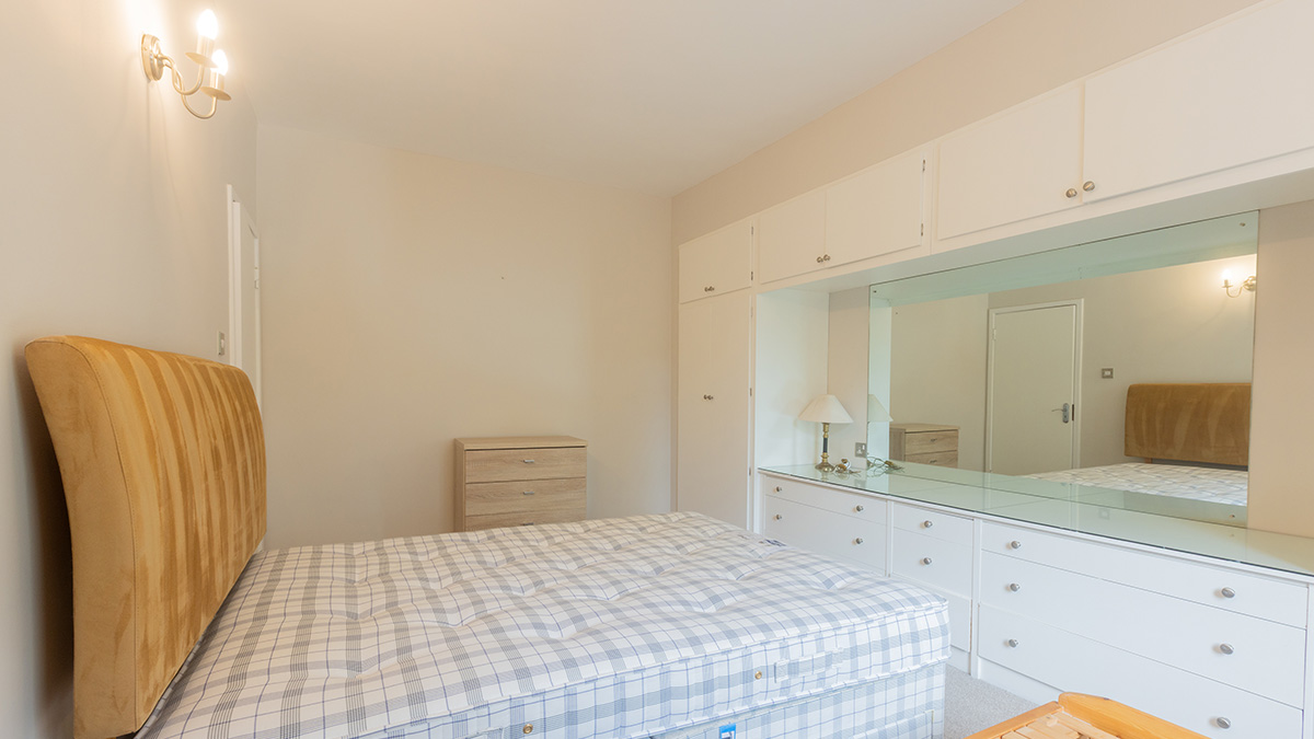 Master bedroom with built-in white cabinetry, large mirror, and unmade bed at 48 Montrose Court before styling
