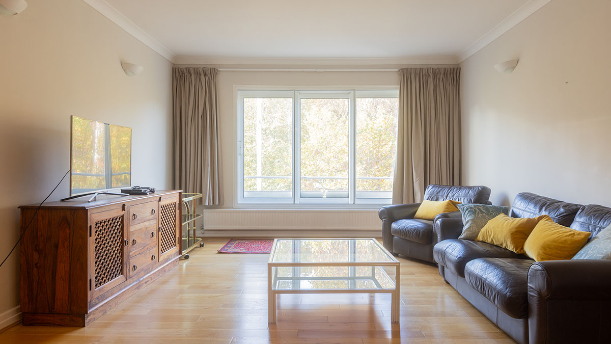 Unfurnished living room with leather sofa, glass coffee table, and wooden TV cabinet at 48 Montrose Court before styling
