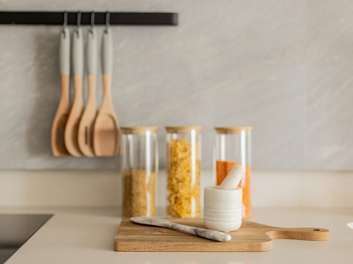 Kitchen countertop with wooden chopping boards, glass storage jars, and hanging utensils in an Oval Village apartment.