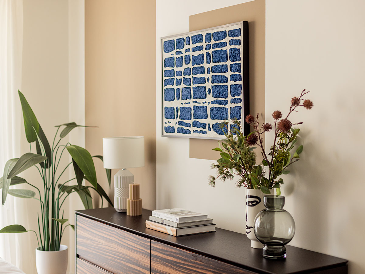 Modern living room decor in Oval Village with abstract art, a large plant, and stylish vases on a dark wood cabinet