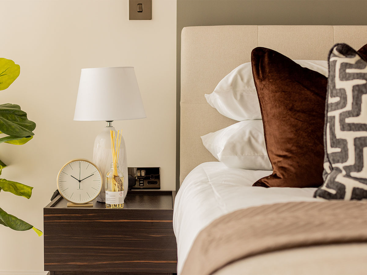 Elegant master bedroom detail in Oval Village, featuring a plush bed, sophisticated lamp, and bedside table
