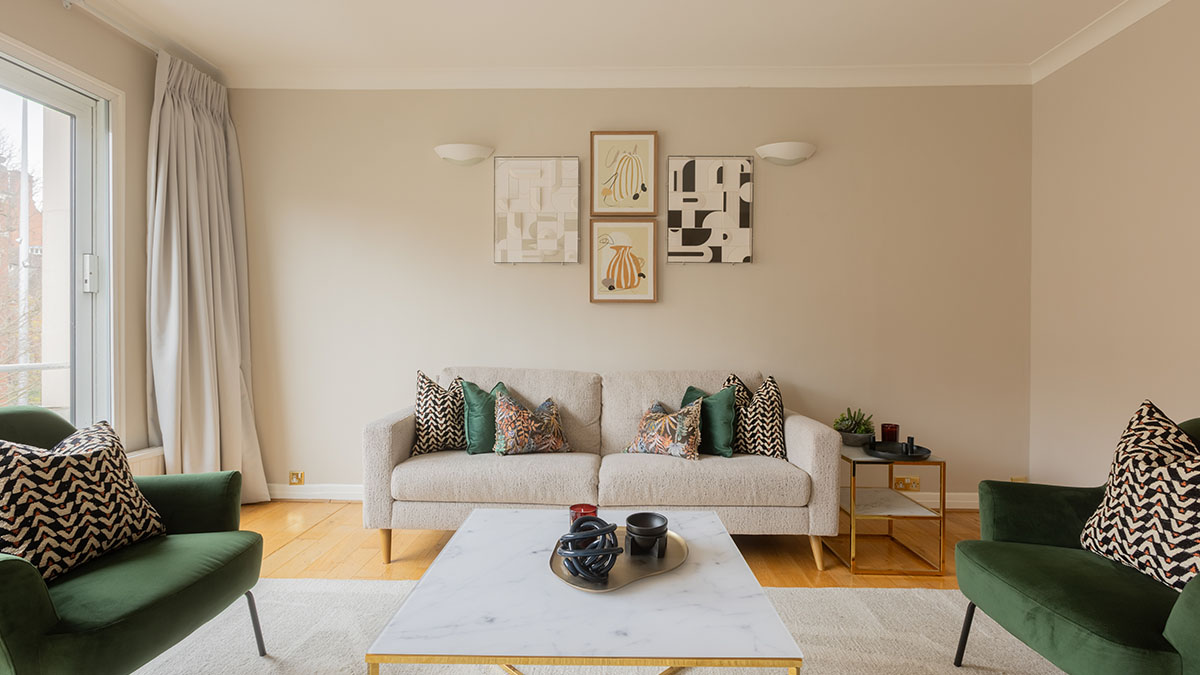 Neutral-toned living room with curated artwork and green accent chairs