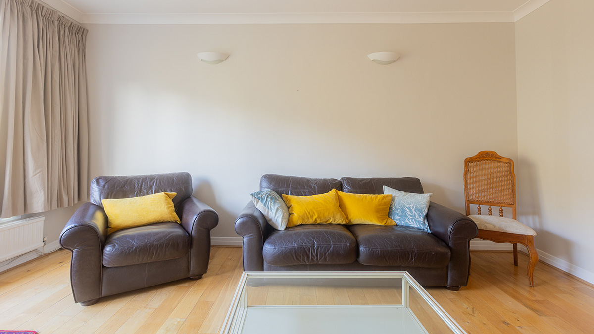 Outdated living room with brown leather sofas and yellow cushions