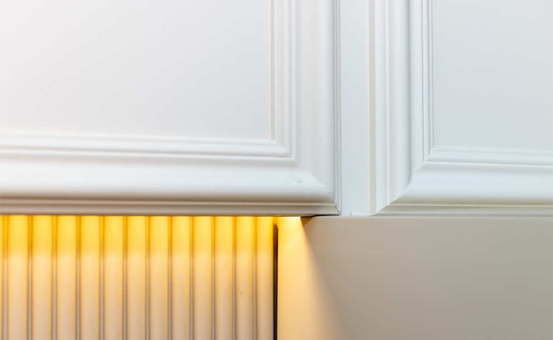 Close-up detail of bespoke interior joinery with warm under-cabinet lighting, showcasing high-quality finishes in a London property renovation