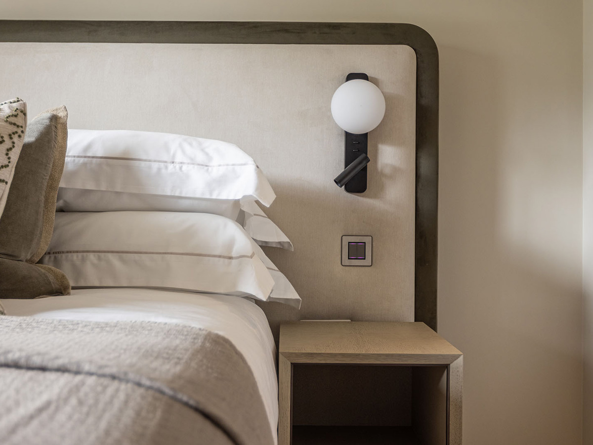 Bespoke upholstered headboard and modern bedside lighting in a furnished apartment bedroom