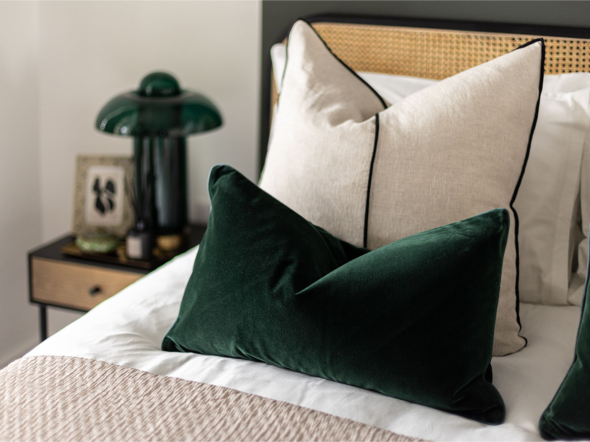 Close-up of a luxurious bedroom with green velvet and cream pillows, part of an InStyle Direct furnishing package for a London flat