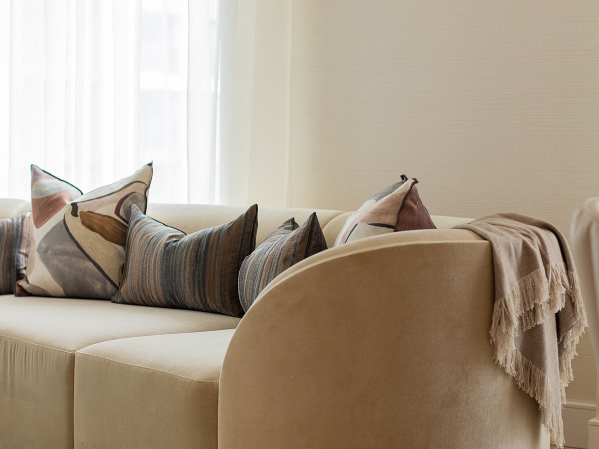 Plush sofa with stylish cushions and throw, highlighting luxury furnishing packages for London rentals
