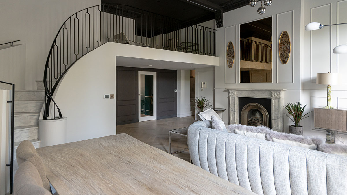 After image of a luxury London flat living area with a curved staircase, plush seating, and a fireplace, exemplifying high-end furnishing packages