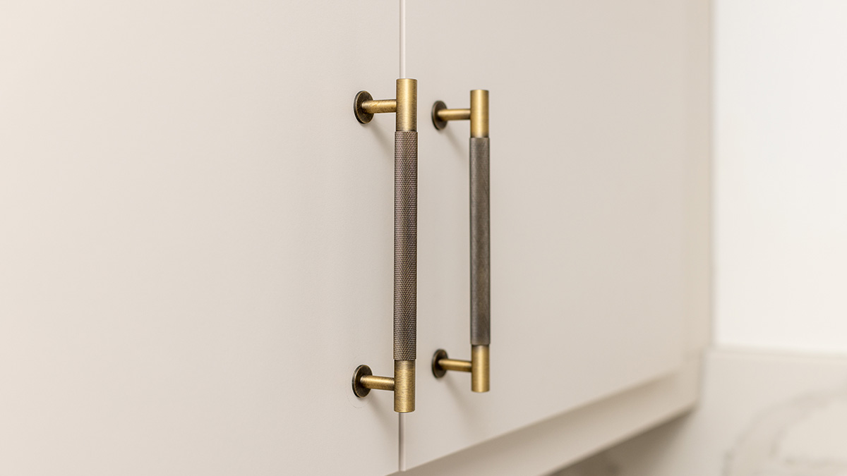 Close-up of elegant gold and textured cabinet handles, showcasing high-end hardware details in a professionally renovated London flat