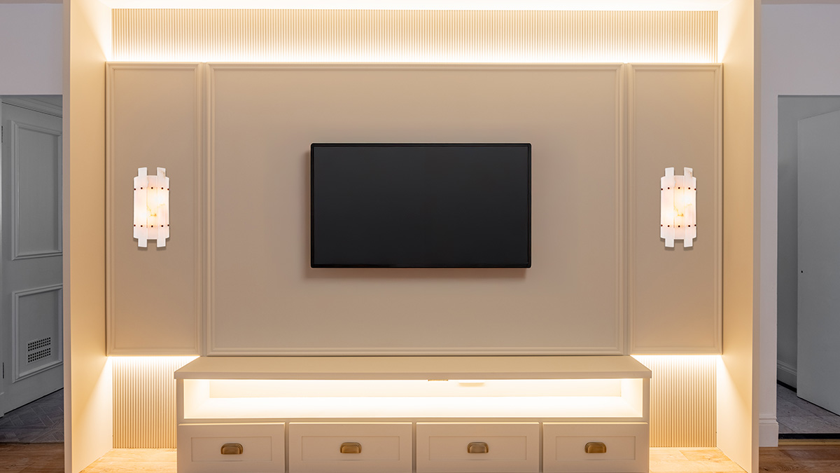 Luxurious living room media wall in a London flat, featuring integrated lighting, decorative panelling, and a mounted television, a prime example of professional design