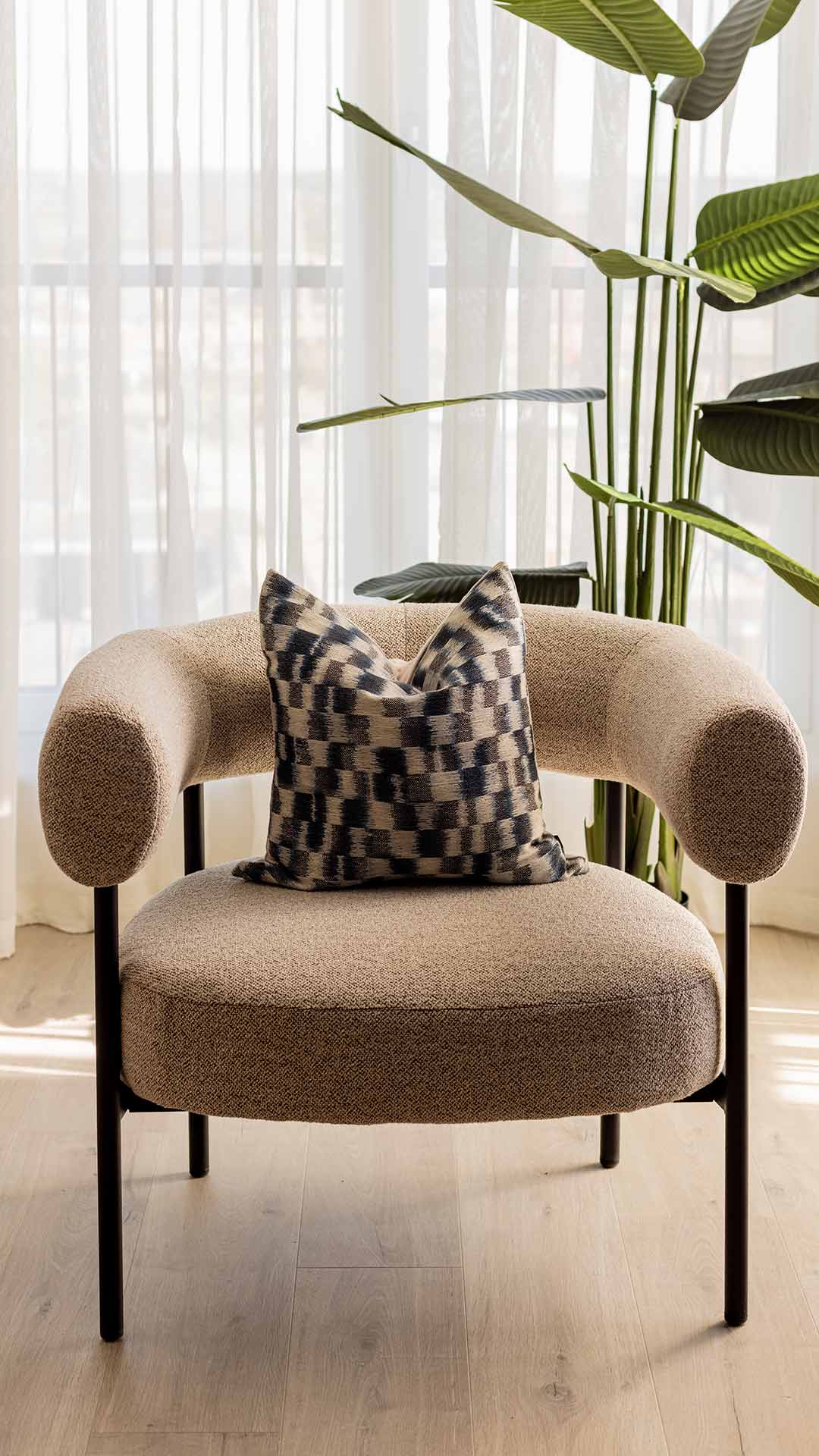 Stylish beige accent chair with a geometric patterned cushion in a light-filled room at Meridian One, demonstrating quality furnishing