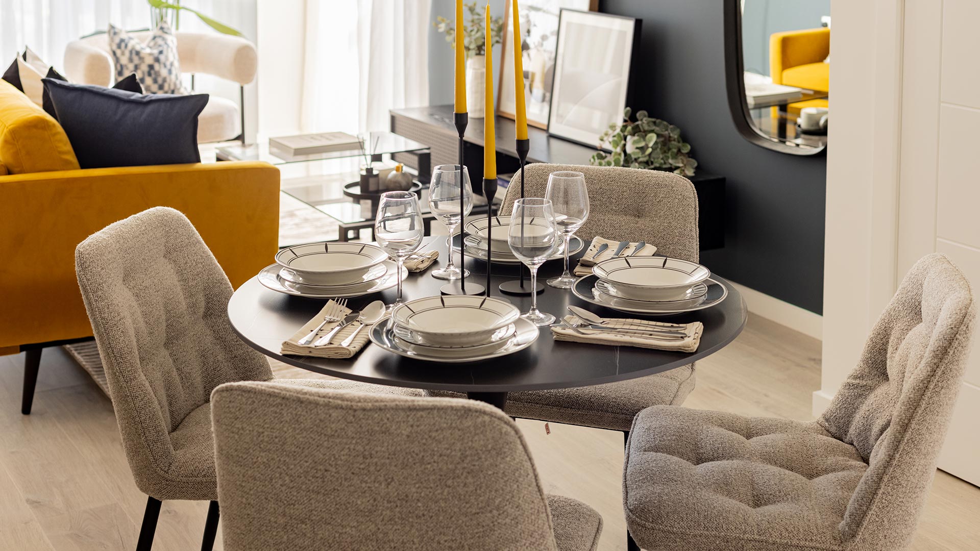 Open-plan dining and living area at Meridian One, featuring a set dining table, grey chairs, and a yellow sofa