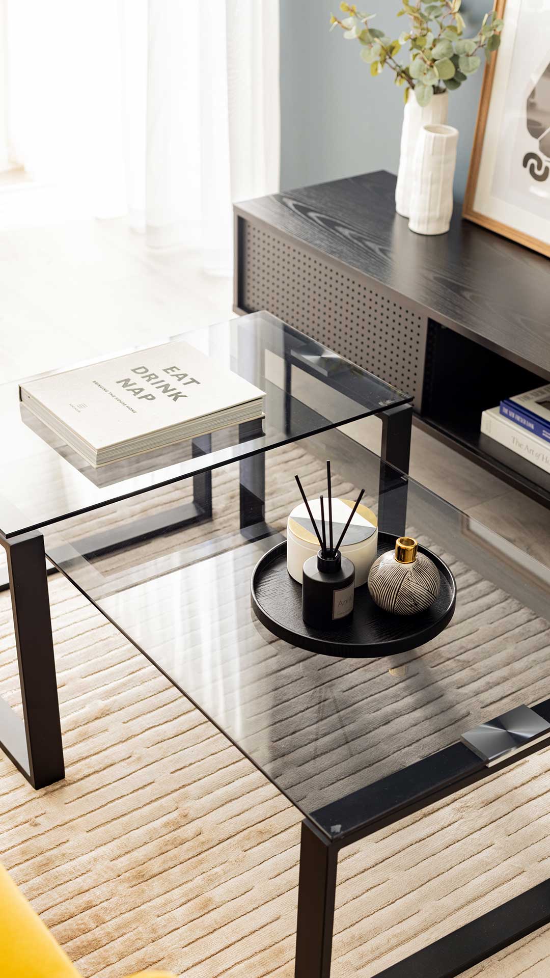 Overhead view of a modern glass coffee table with a book and decorative tray, enhancing a Meridian One living space