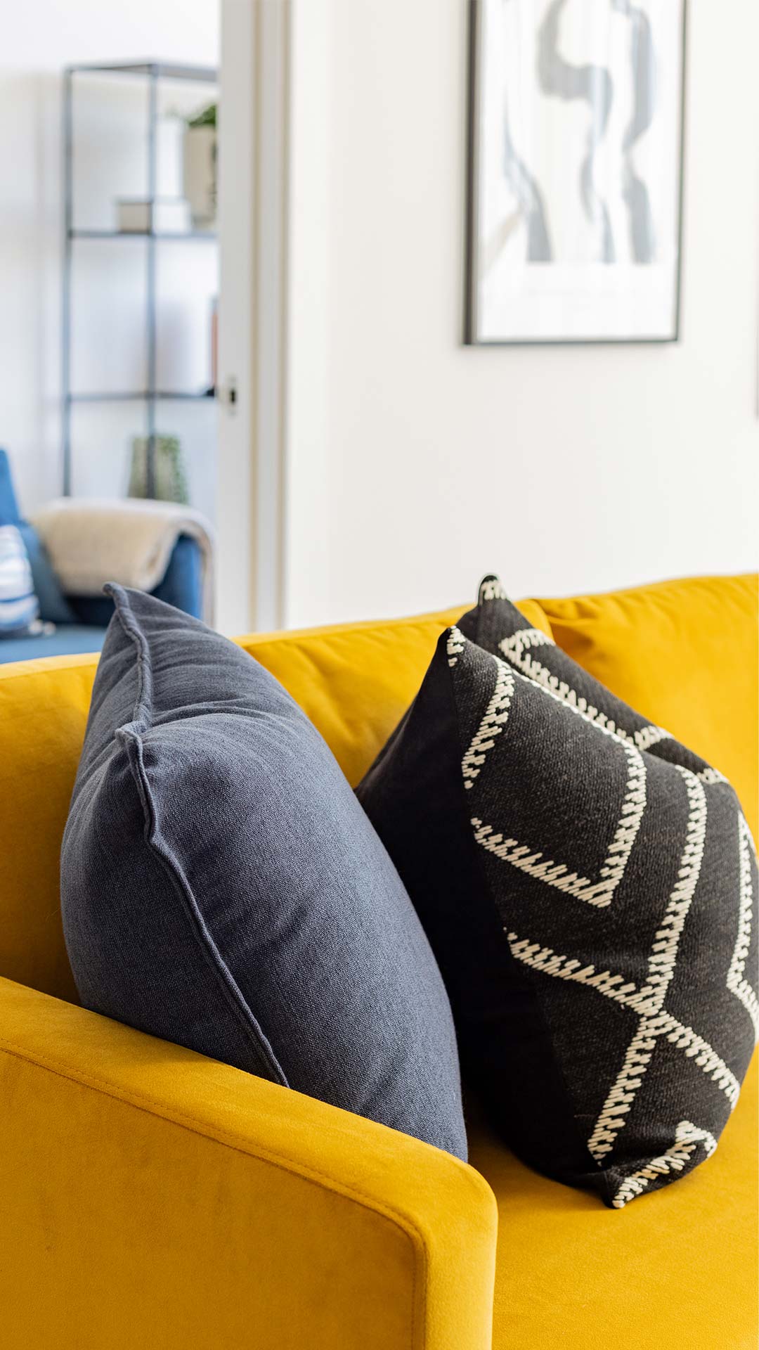 Close-up of blue and black patterned cushions on a vibrant yellow sofa, showcasing texture and color in a Meridian One living room