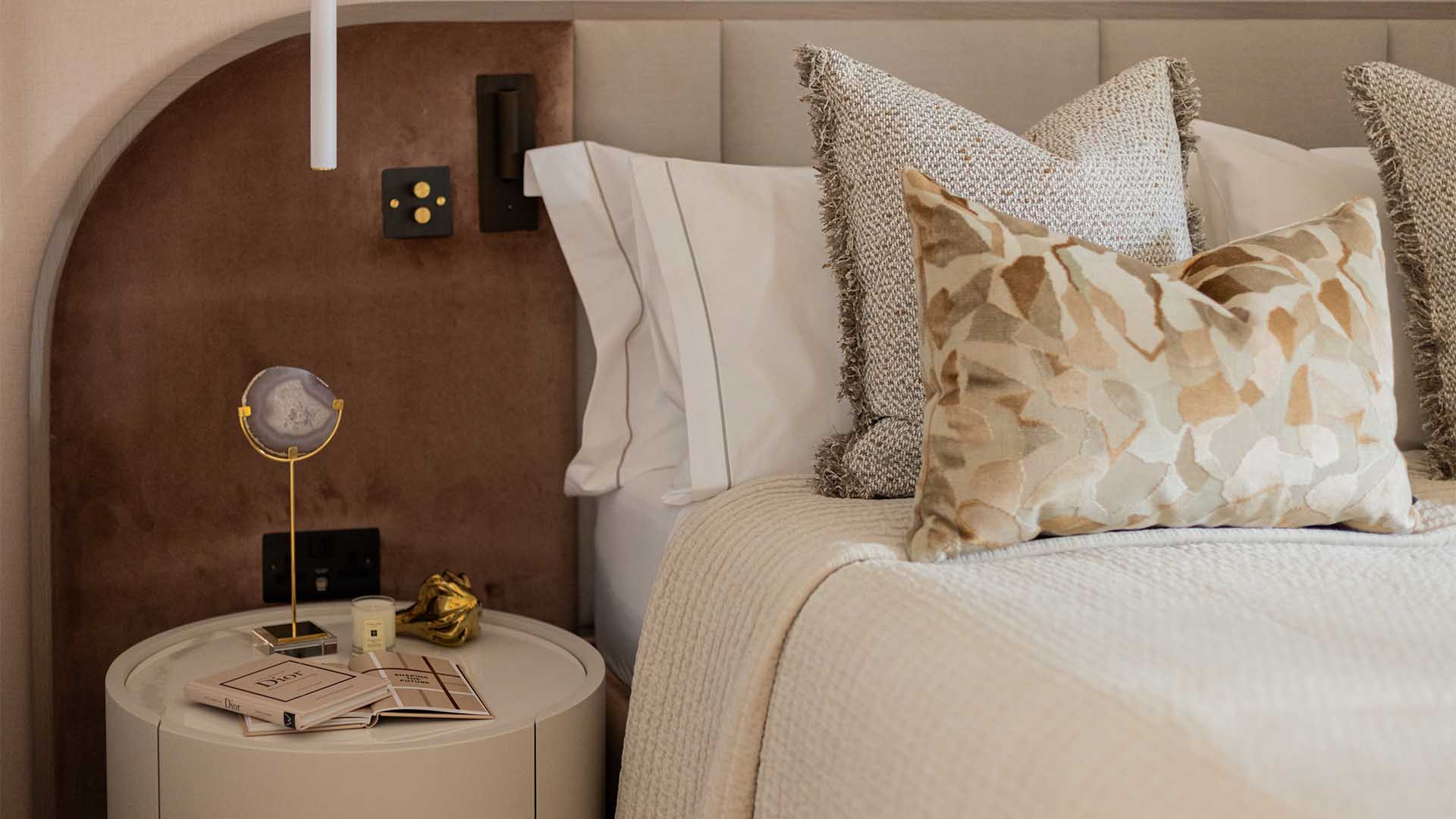 Detailed view of a professionally styled bedside table with a lamp and decorative items in a London flat